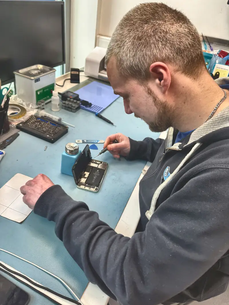 Technicien réparant un smartphone à l'établi du magasin Mister Genius de Woluwe-Saint-Lambert